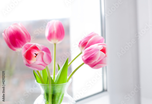 Bouquet of pink tulips in vase on the window. Springtime. Close-up. Selective focus.