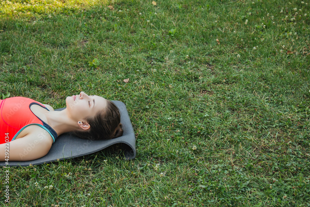 European girl in a light tracksuit doing yoga in the park in the afternoon in the summer. Gymnastics in nature. Thin woman outdoor European girl in a light tracksuit doing yoga in the park in the afternoon in the summer. Gymnastics in nature. Thin woman outdoor