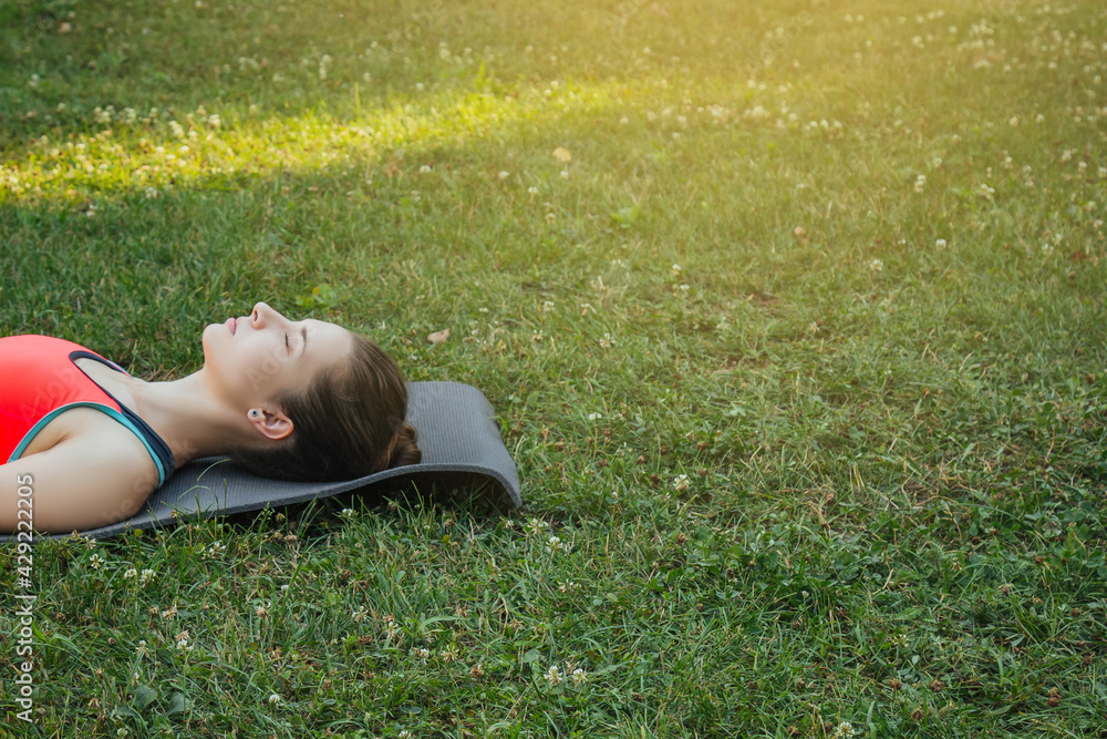 European girl in a light tracksuit doing yoga in the park in the afternoon in the summer. Gymnastics in nature. Thin woman outdoor European girl in a light tracksuit doing yoga in the park in the afternoon in the summer. Gymnastics in nature. Thin woman outdoor