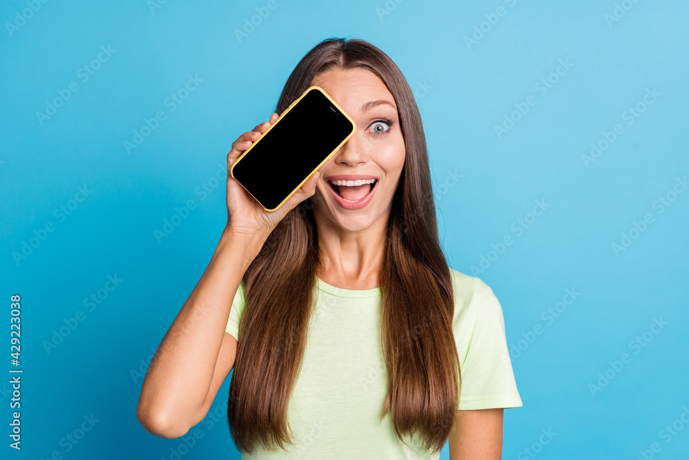 Photo of impressed brunette lady cover eye by telephone wear light t-shirt isolated on blue color background Photo of impressed brunette lady cover eye by telephone wear light t-shirt isolated on blue color background