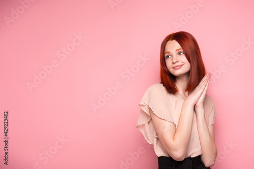 The red-haired girl is bright  sweet and gentle. On a pink solid background. Transparent healthy skin.