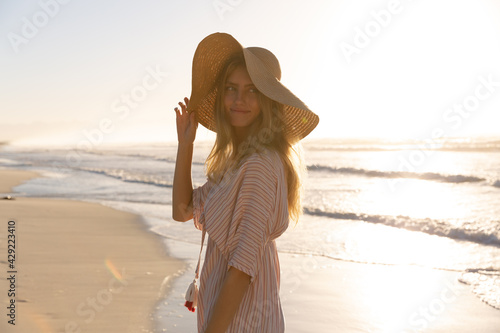 Caucasian woman wearing beach cover up and hat having fun at the beach photo