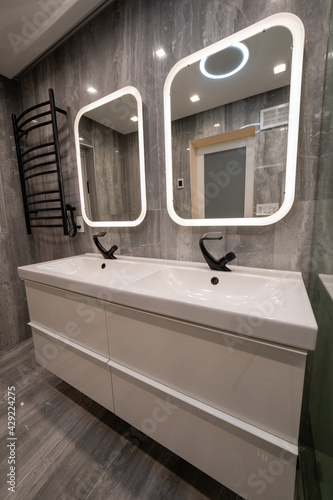 Modern bathroom with double sink, mirrors and towel rack