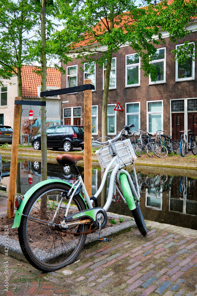 Bicycle parked near the canal in Delft street with old houses. Delft, Netherlands