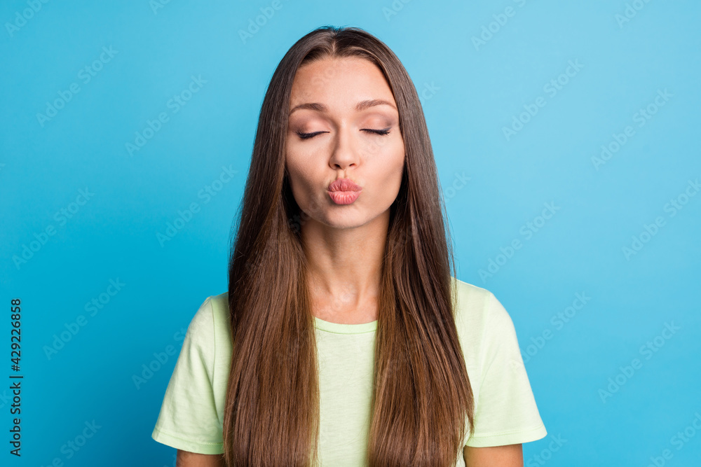 Photo of pretty adorable young lady wear green t-shirt closed eyes sending kiss isolated blue color background Photo of pretty adorable young lady wear green t-shirt closed eyes sending kiss isolated blue color background
