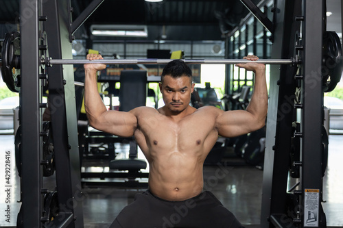 A Man Pumping Up Muscles with Weight Lifting Machine in a Gym