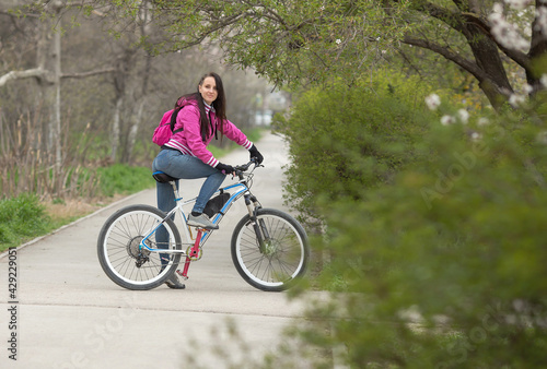 sporty girl rides a bicycle on a pedestrian path, spring landscape.