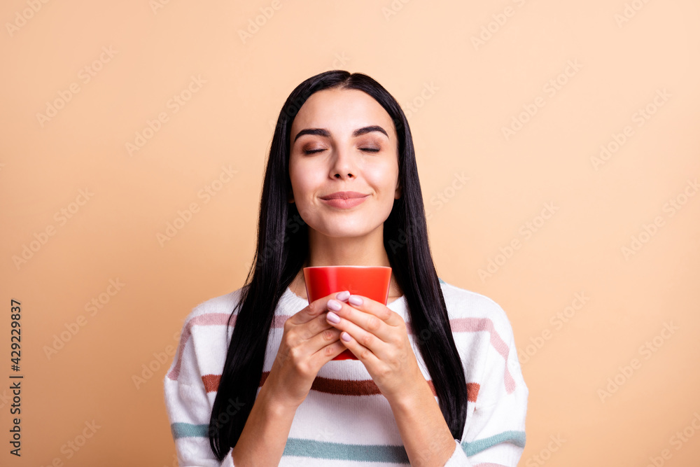 Photo of young attractive woman happy positive smile enjoy aroma smell of morning coffee isolated over beige color background Photo of young attractive woman happy positive smile enjoy aroma smell of morning coffee isolated over beige color background