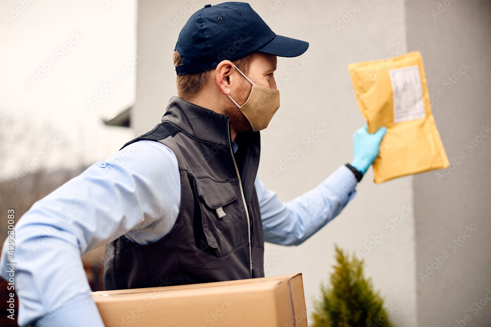 Courier wearing face mask while making home delivery during coronavirus pandemic. Courier wearing face mask while making home delivery during coronavirus pandemic.