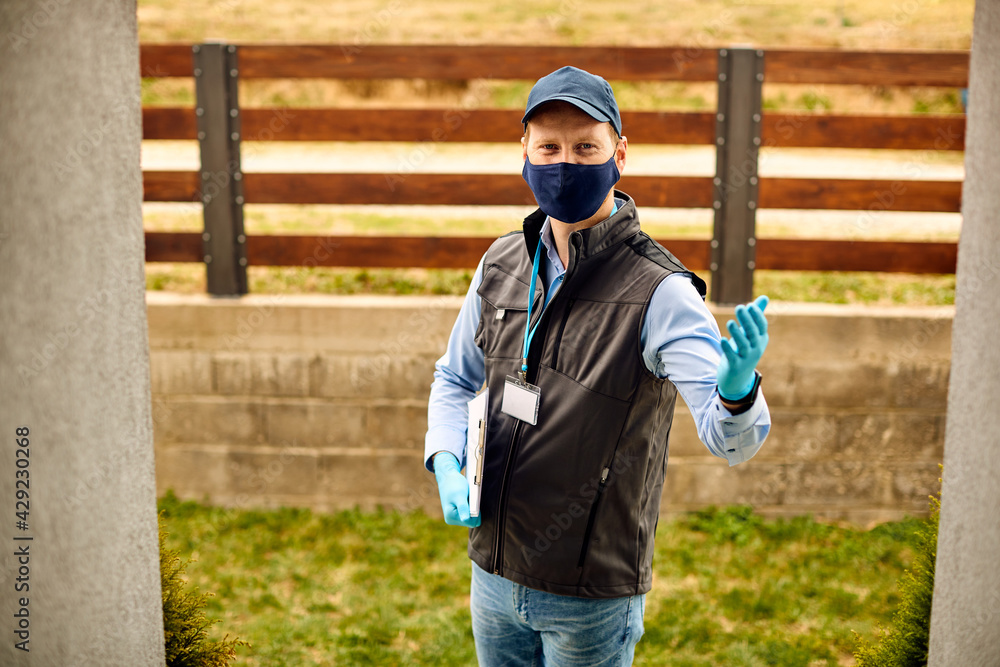 Smiling male courier wearing protective face mask  and gloves during home delivery due to COVID-19 pandemic.