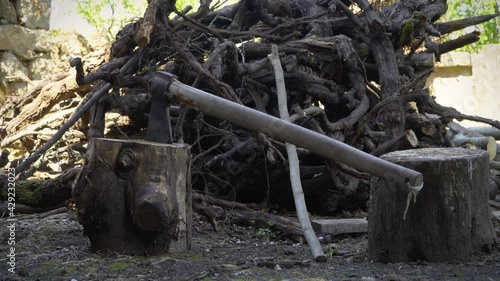 ax stuck in a piece of wood with remnants of wood behind it. Black wooden ax with a wooden handle and behind the remains of dried cut vines. ax chopped wood and wood on the ground