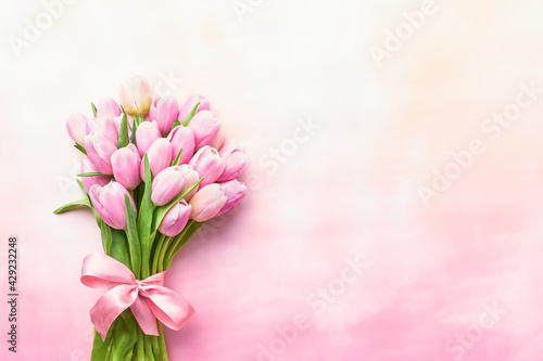 Fototapeta Naklejka Na Ścianę i Meble -  Pink tulips bouquet decorated with ribbon on a pink background. Mothers Day, Valentines Day, bachelorette concept.