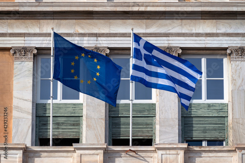 Athens, Attica, Greece. European Union's and Greece's flags waving in front of the greek parliament neoclassical building. Sunny day