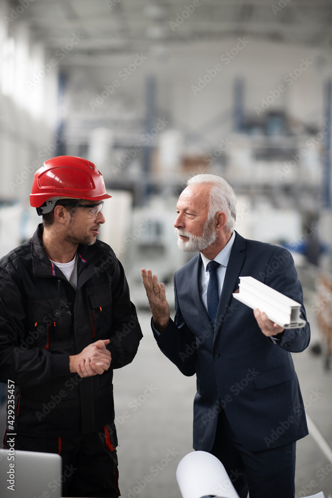 Architect and worker working on project. Colleagues working in factory.. Architect and worker working on project. Colleagues working in factory..