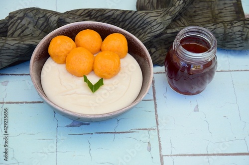 Bubur Sumsum Biji Salak, Indonesian rice flour porridge with sweet potato glutinous rice balls, served with palm sugar sauce, garnish with pandan leaf. Popular food during Ramadan photo