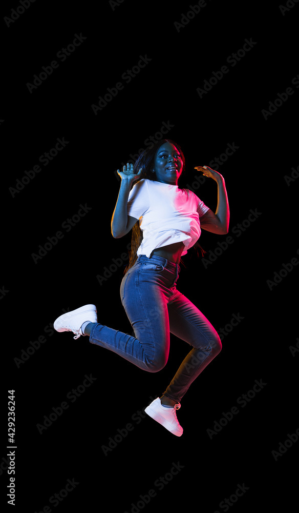 African young woman's portrait on dark studio background in neon. Concept of human emotions, facial expression, youth, sales, ad.