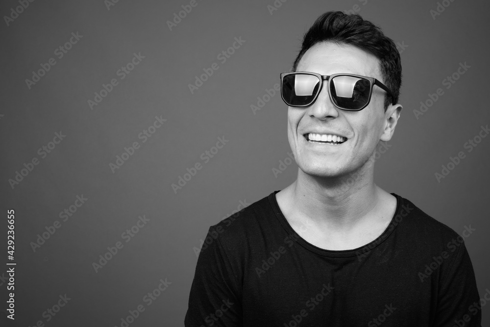 Obraz premium Young handsome Hispanic man against gray background
