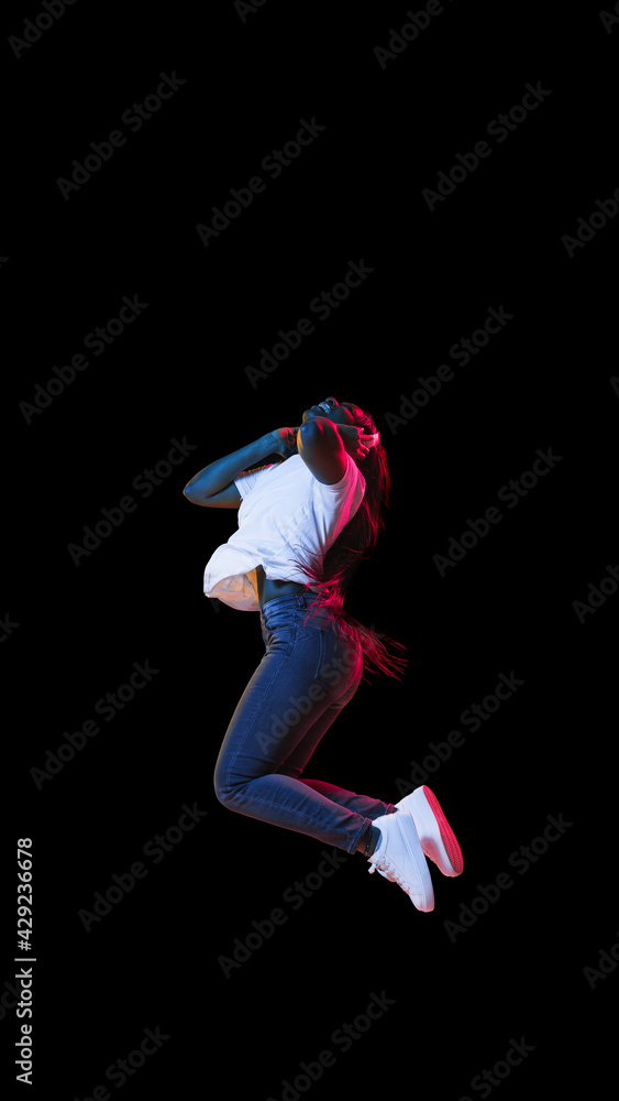 African young woman's portrait on dark studio background in neon. Concept of human emotions, facial expression, youth, sales, ad.