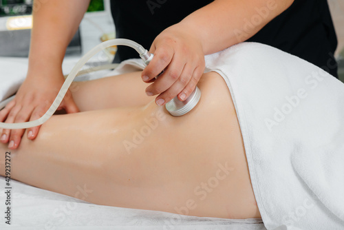 A young pretty girl is enjoying a professional vacuum massage at the Spa. Body care. Beauty salon