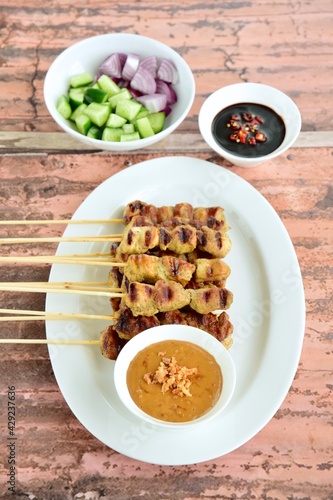 Indonesian chicken satay or Sate Ayam. Served with sweet soy sauce  peanut sauce and pickles cucumber and onion