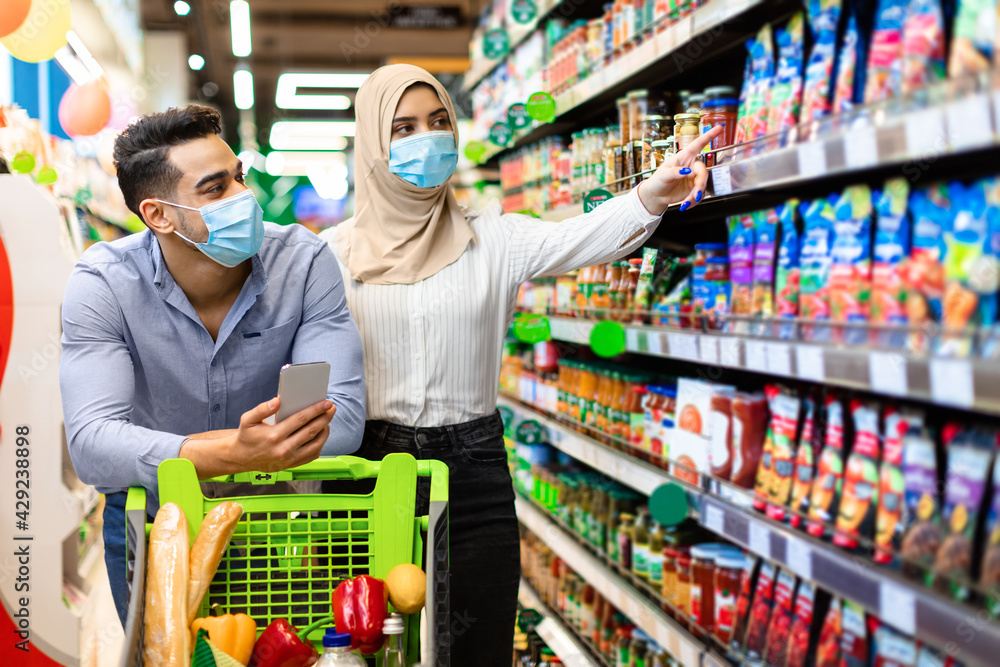 Muslim Couple Choosing Food In Supermarket Doing Grocery Shopping Together