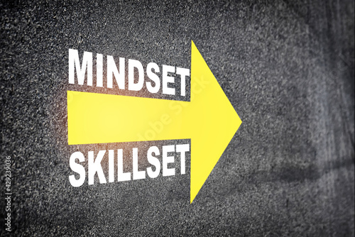 Mindset and skillset written on asphalt road surface with yellow arrow symbol. Self development to success concept and challenge idea photo