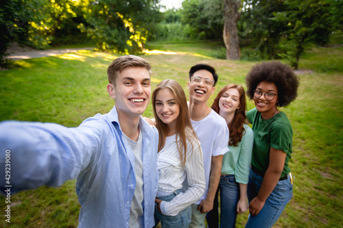 Group of multiethnical teen friends talking selfie outdoors in park