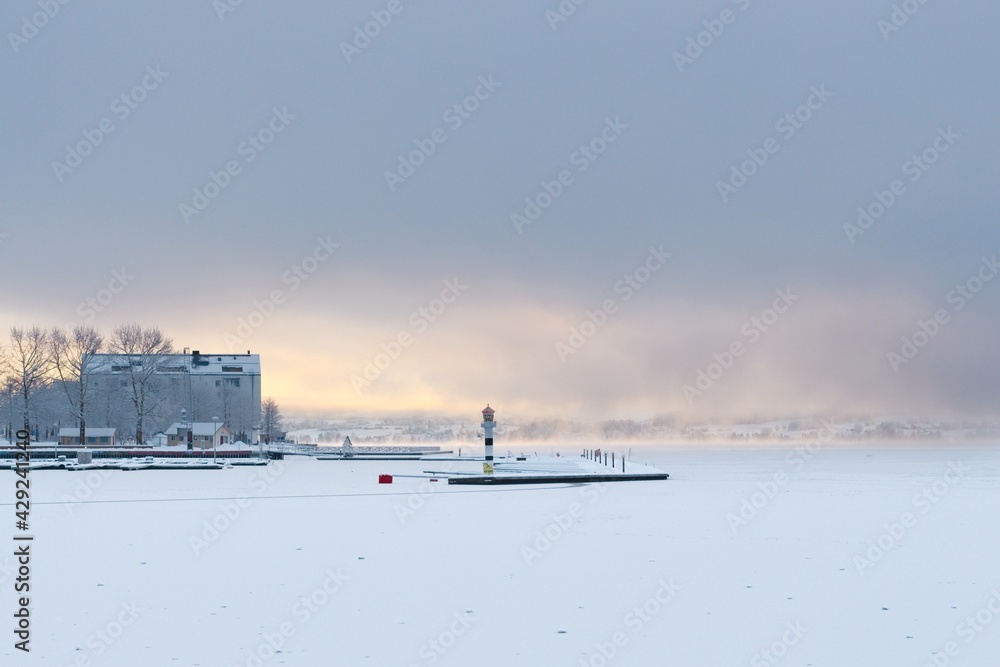 View of the frozen and snow-covered Storsjön Lake in Östersund in the light of sunset