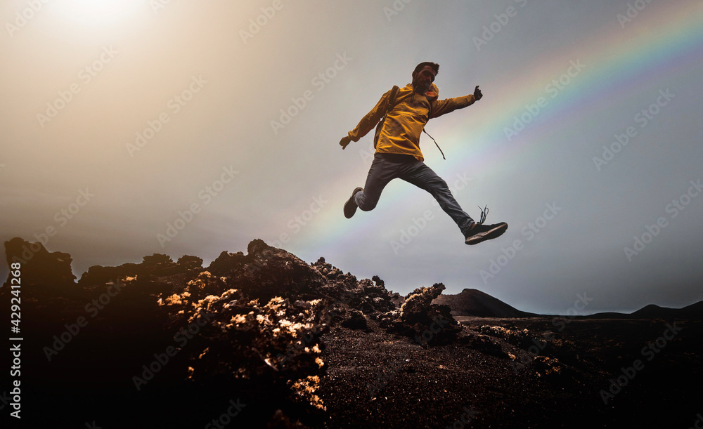 Man jump through the gap over the mountain rocks at sunset