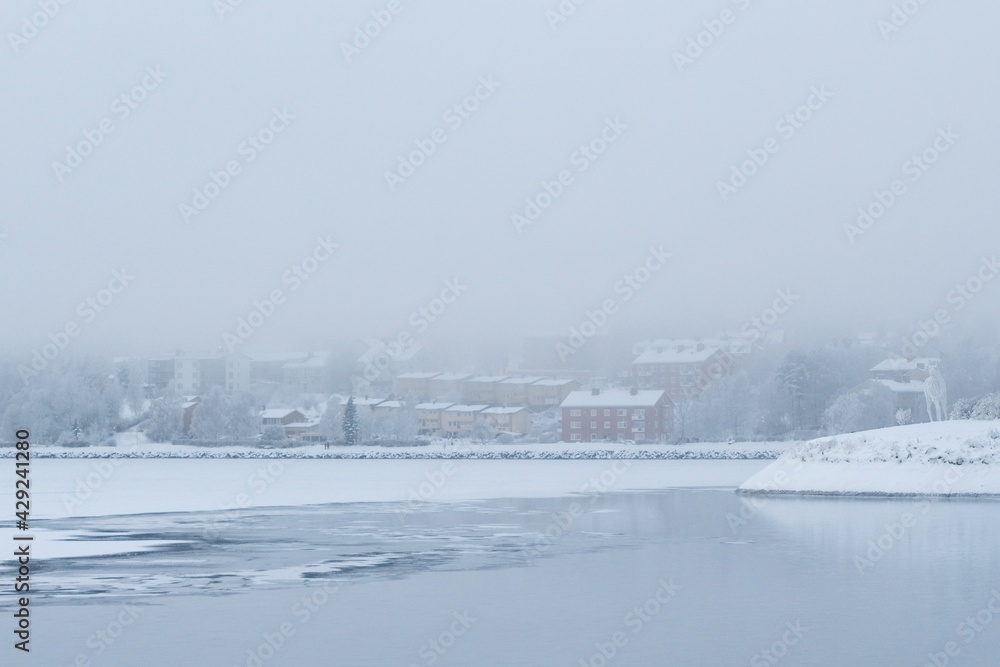 Fototapeta premium View of the Fröson Island covered with winter fog as seen from Badhusparken in Östersund