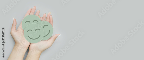 Hand holding group of green paper cut happy smile face, positive thinking, mental health assessment , world mental health day concept