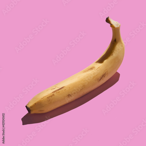 Colorful ripe yellow peeled banana on pink background. Pattern concept.