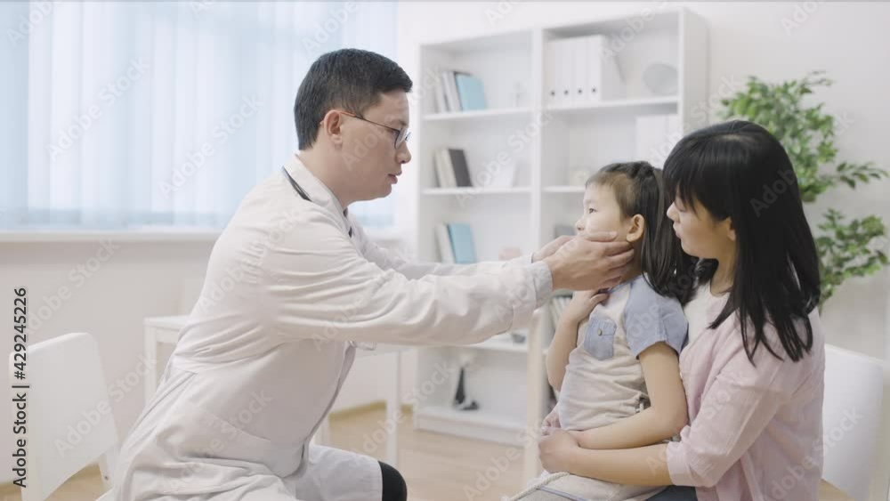 ENT doctor examining asian little girl, consulting mother and child in hospital ENT doctor examining asian little girl, consulting mother and child in hospital