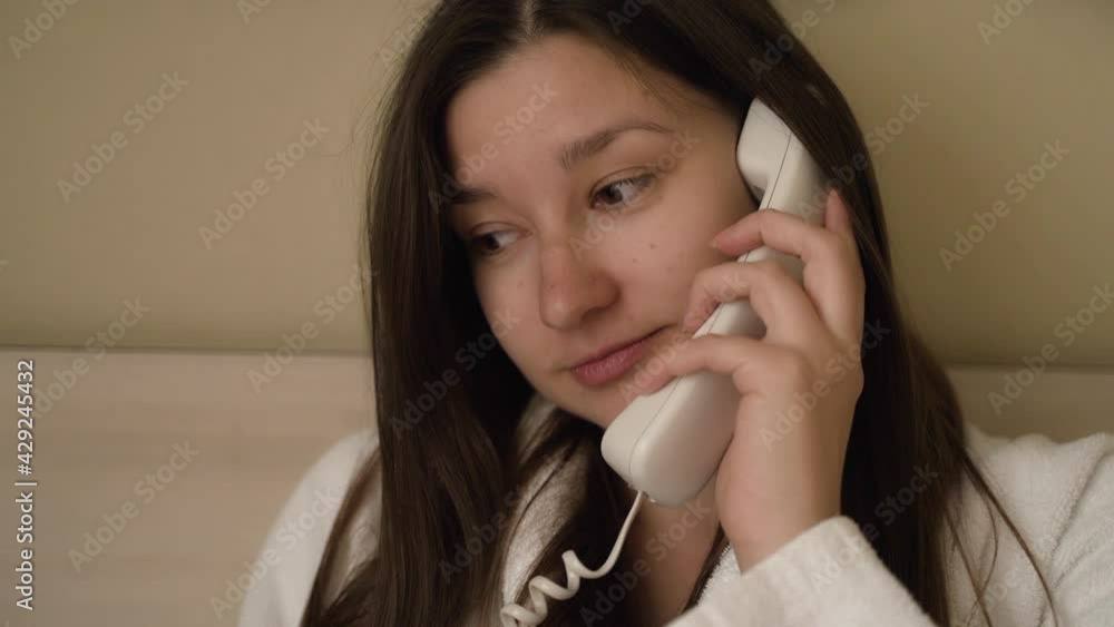 Young brunette woman speaks on a wired white phone Young brunette woman speaks on a wired white phone