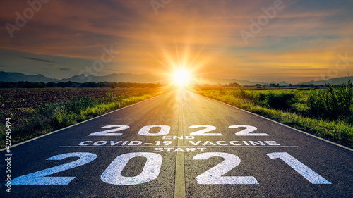 Vaccination 2021 concept.Word 2021 start covid-19 vaccine end 2022 written on the road in the middle of asphalt road at sunset.Concept of got coronavirus covid-19 vaccine and end 2022
