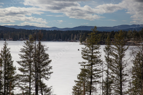 Frozen northern lake amongst pines and mountains © Marcy