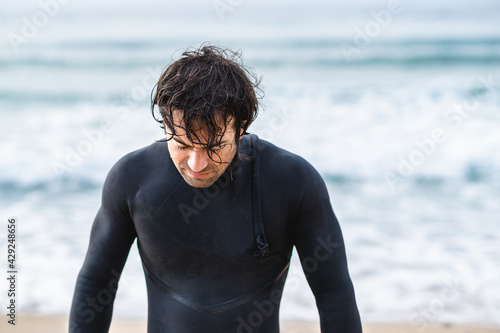 Medium shot young wet man with diving suit getting out of the sea