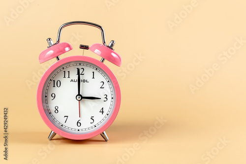 Pink alarm clock on a beige background. Time Concept. Place for your text.