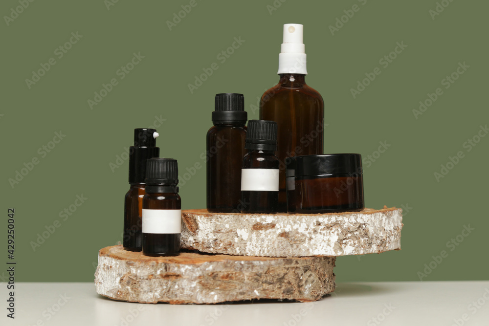 Various brown glass cosmetics bottles on green background
