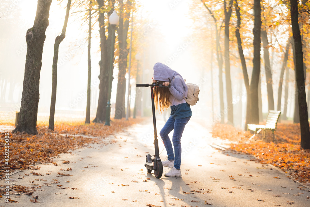 Cute teenage girl on scooter in autumn park Cute teenage girl on scooter in autumn park