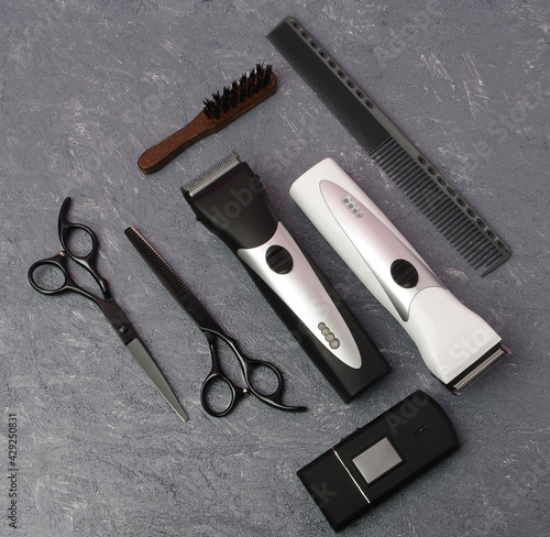 Professional Hairdressing Tools on a Gray Marble Background. Scissors and Thinning Shears, Hair Clippers and Shaver, Comb and Brush Stylized in Classic Black and White Colors With Metal Blades. 