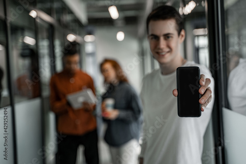 Wallpaper Mural happy student holding smartphone with blank screen near interracial classmates on blurred background Torontodigital.ca