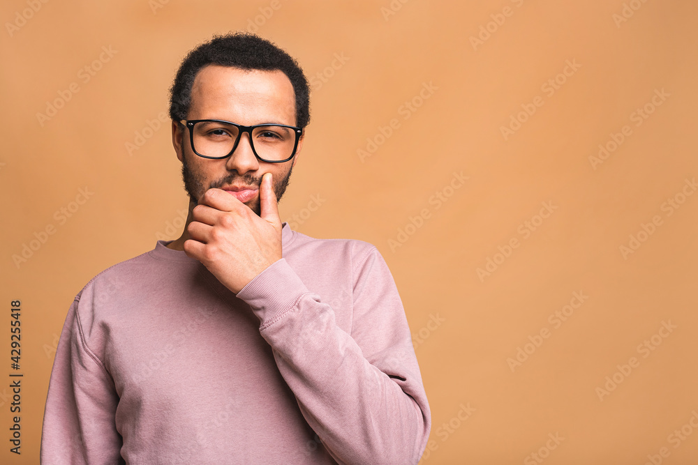 Thinking black Afro American man with serious expression looking, posing isolated against beige background. Thinking black Afro American man with serious expression looking, posing isolated against beige background.