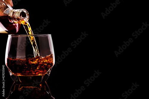 whiskey pouring in glasses with ice cubes isolated on black background. have space for text