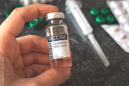 Man hold Vaccine vial in hand, COViD-19 vaccination concept background with syringe