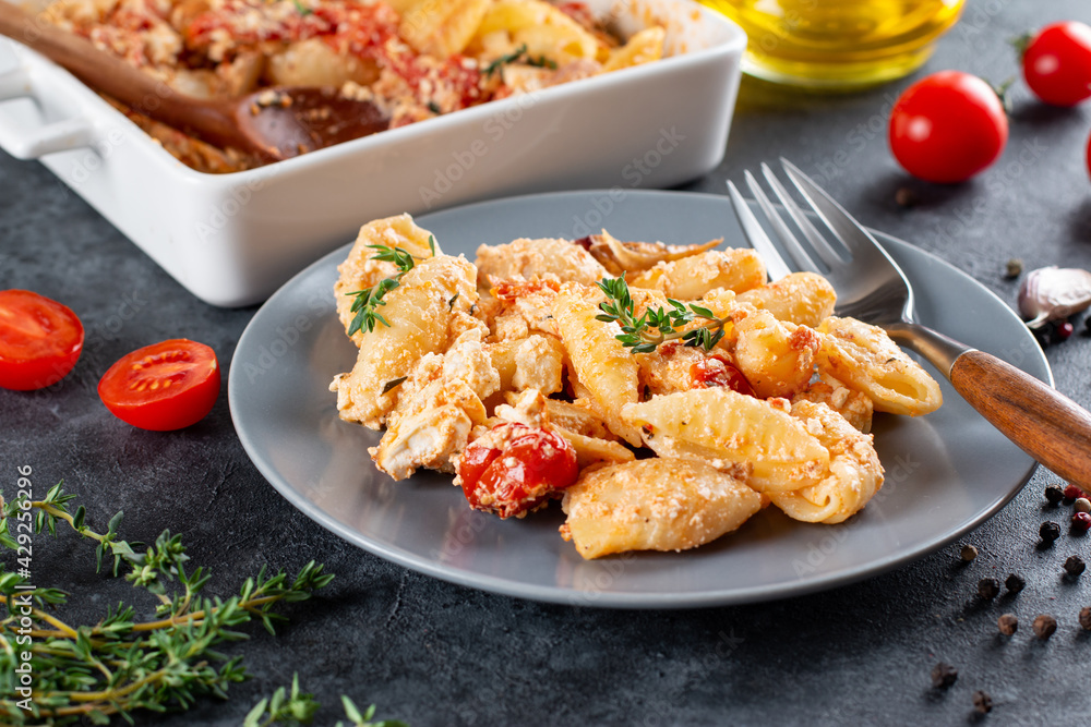 Baked feta pasta ingredients for dinner on a plate on a dark background. Baked feta pasta ingredients for dinner on a plate on a dark background.