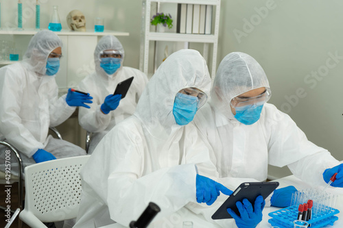 Asian medical scientists in PPE protective suit research for virus pandemic vaccine in clinical laboratory