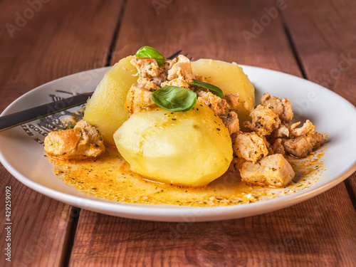 Young boiled potatoes with chicken goulash on a light plate