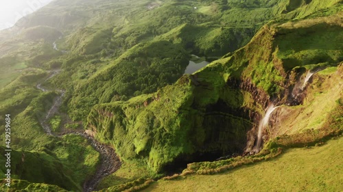 Aerial view of breathtaking landscape of Poco Ribeira do Ferreiro, Alagoinha, Flores Island, Azores, Portugal, Europe. Amazing waterfall flowing in valley with green mountains, 4k footage photo