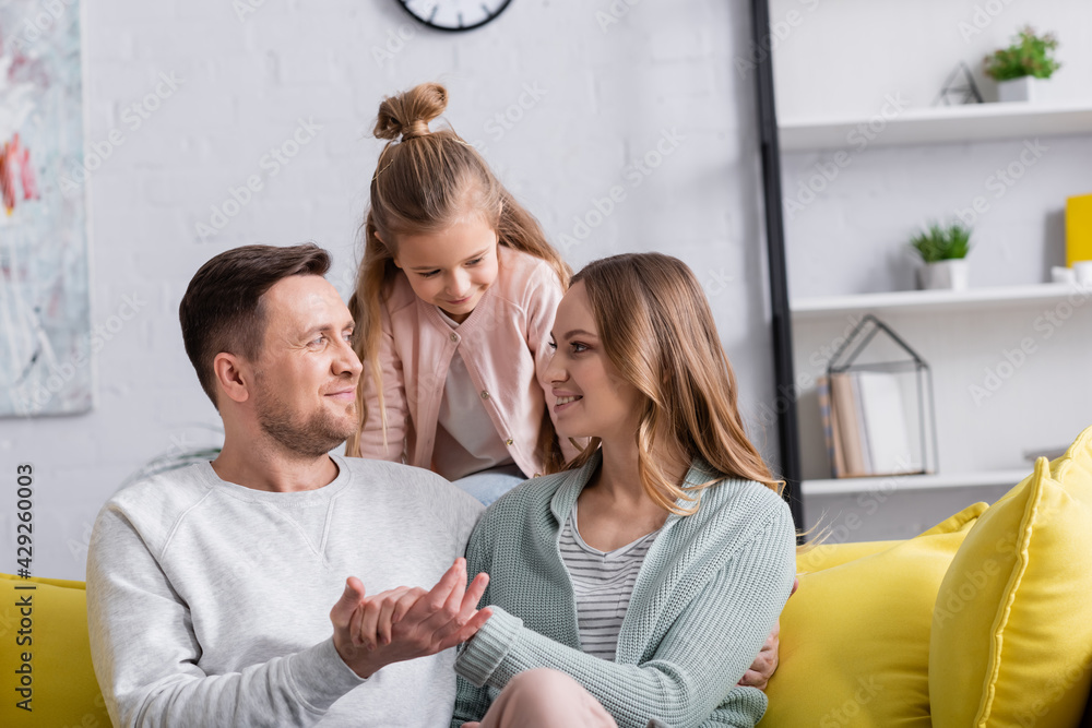 Smiling papers holding hands near daughter at home. Smiling papers holding hands near daughter at home.